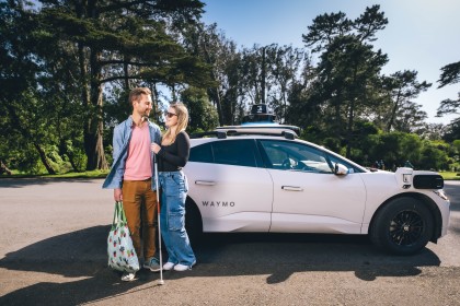 Jessie and her boyfriend Nick posing next to a Waymo vehicle in Golden Gate Park