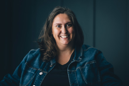 Portrait of Christy Moore, the founder of Social Spin. She has shoulder length brown hair and is wearing a denim jacket.